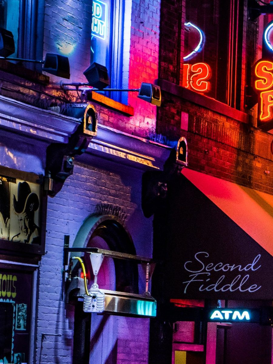 A brick building on Lower Broadway lit purple and pink at night