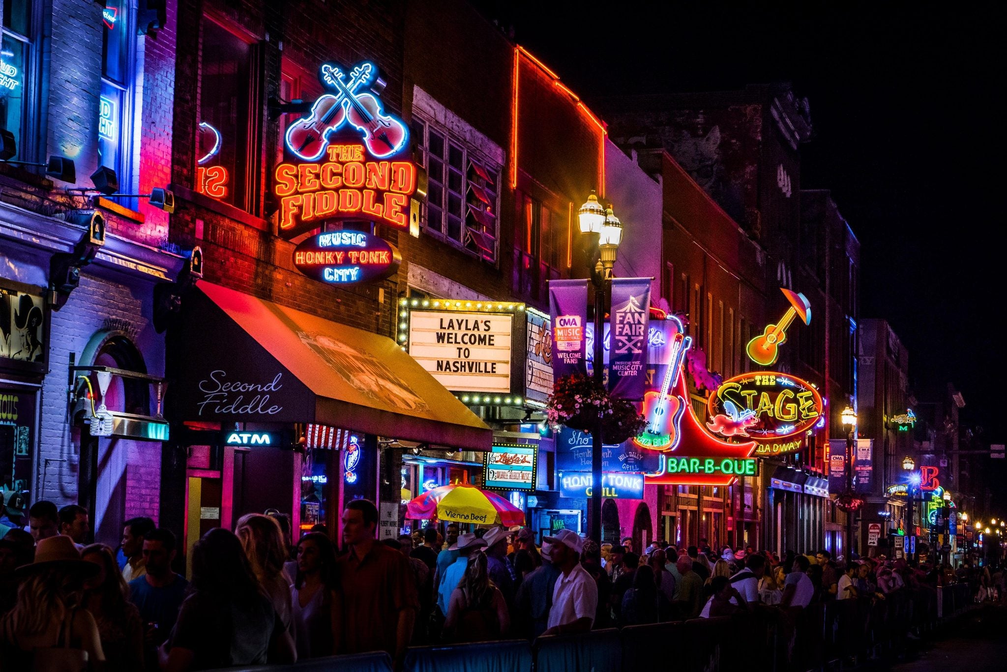 Lower Broadway in Nashville at night: neon signs above a crowd on the sidewalk